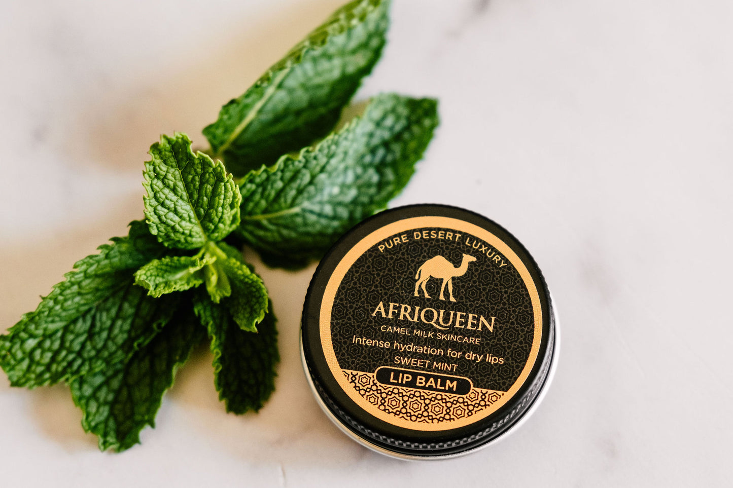 Afriqueen lip balm with mint leaves on a light background
